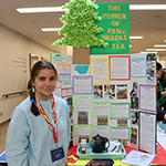 A participant standing in front of their project board.